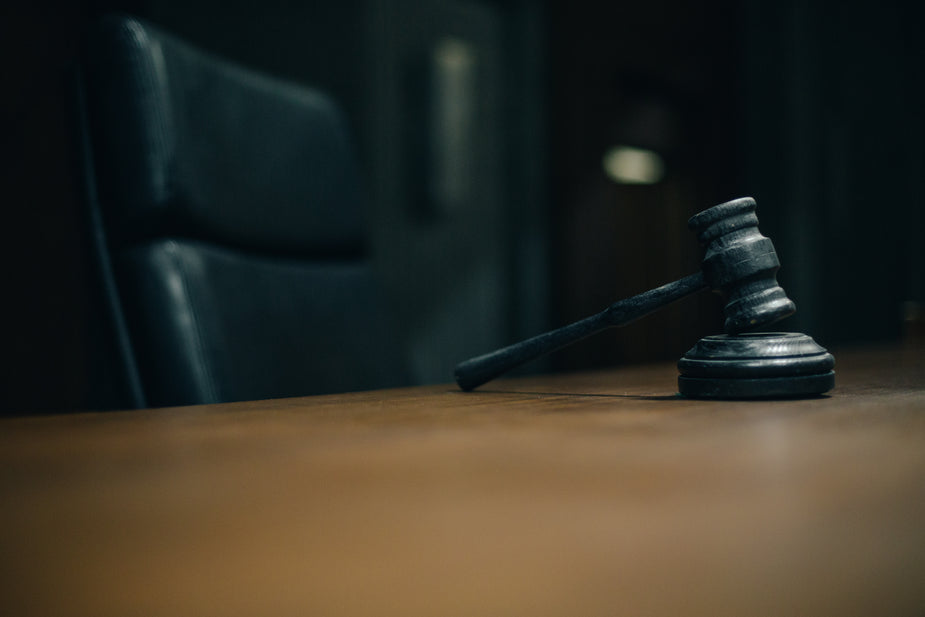 Black gavel on judge's desk and empty black chair